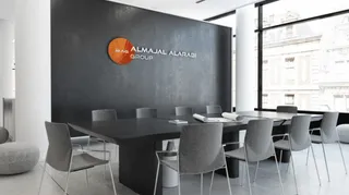 Modern boardroom with a dark feature wall carrying the Almajal Alarabi Group logo