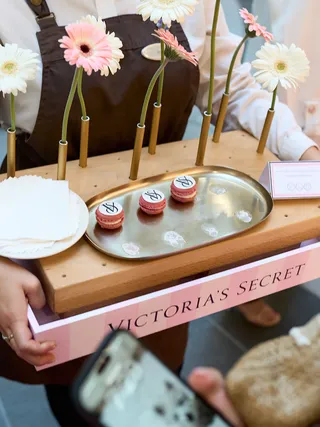 Pink Victoria's Secret box with flowers and mini cakes on a wooden tray